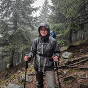 Guide Solomiia Havryliuk in rain gear on a wet mountain descent